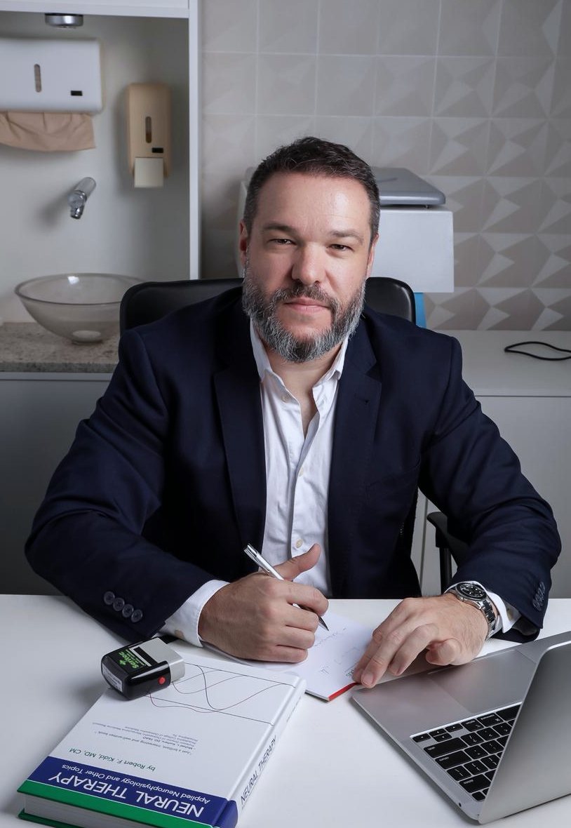 Dr. Ricardo Lazarotto anotando um plano de tratamento na mesa do consultório