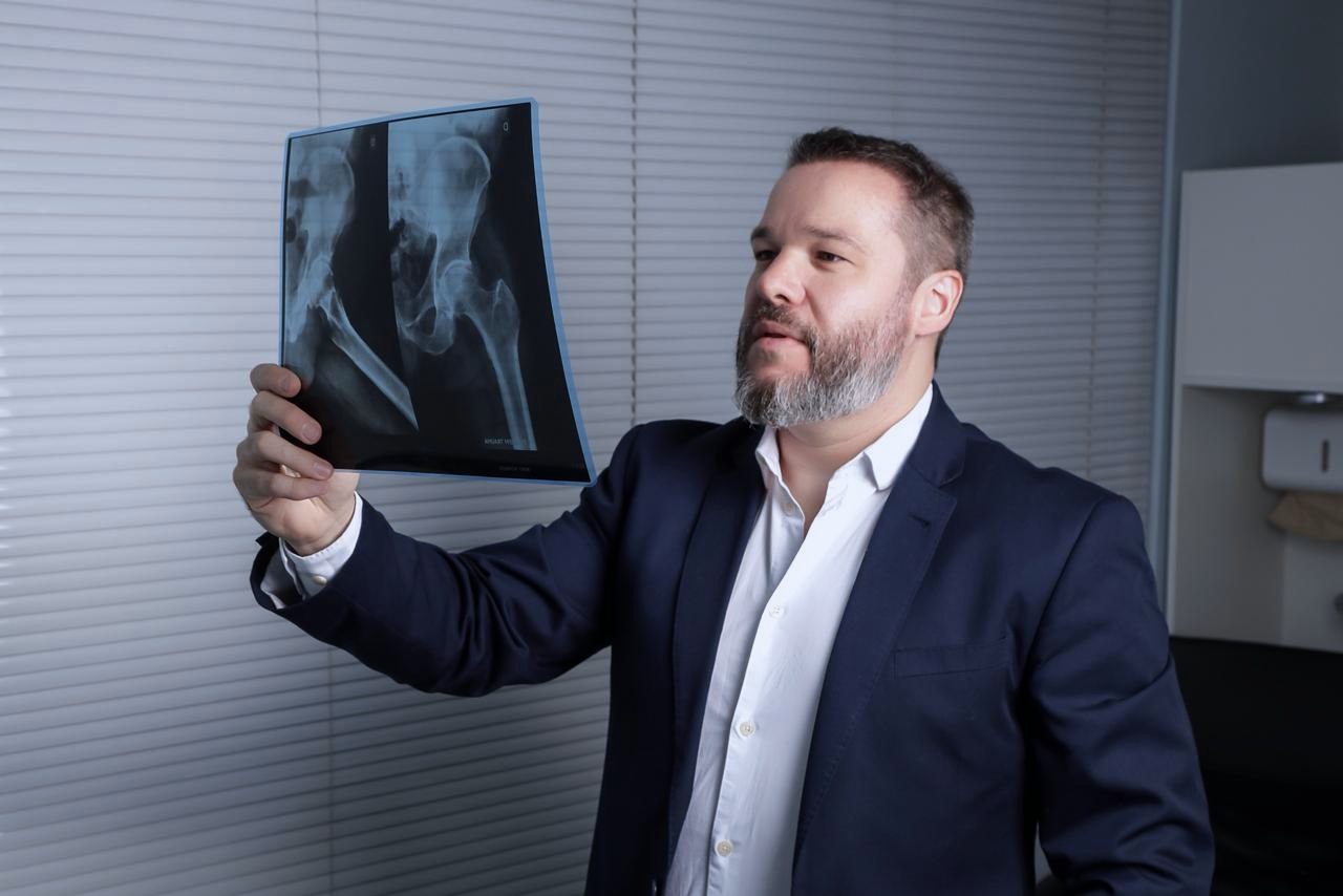 Dr. Ricardo Lazarotto avaliando uma radiografia de quadril contra a luz